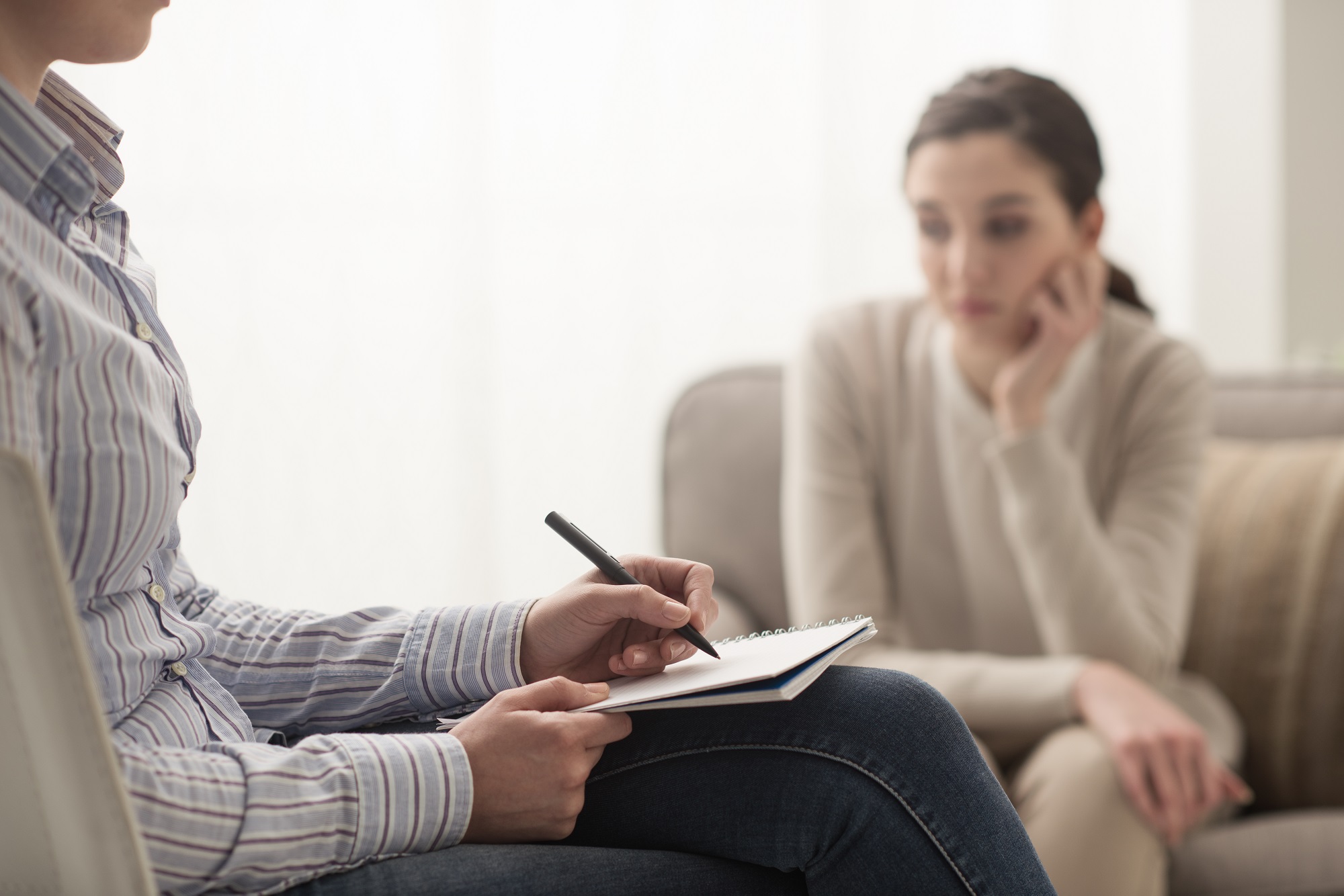 Close-up of woman's hands during counseling meeting with a professional therapist. Box of tissues and a hand of counselor blurred in the front.